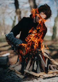 Midsection of man with fire on log