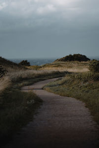 Footpath leading towards beach against sky