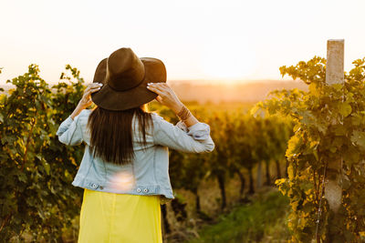 Rear view of woman standing by plants against sky