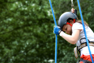 Adventure climbing high wire park - people on course in mountain helmet and safety equipment.