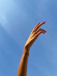 Low angle view of hand against clear blue sky