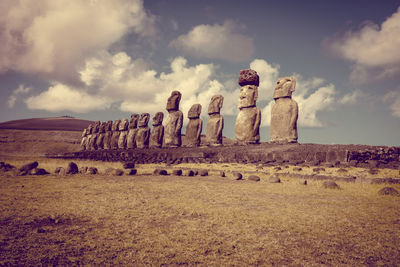 Stone structure on field against cloudy sky