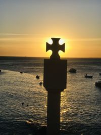 Silhouette wooden post on beach against sky during sunset