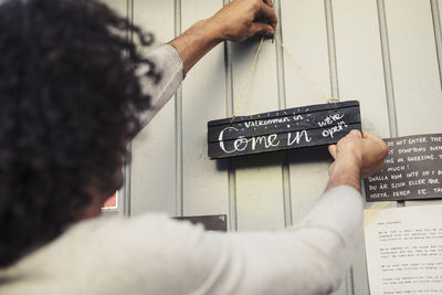 Male entrepreneur hanging open placard sign on door at organic shop