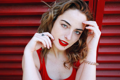 Portrait of beautiful young woman standing against window