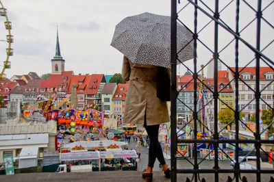 Rear view of woman with umbrella by gate in city