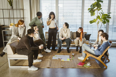 Multiracial male and female colleagues discussing during meeting in creative office