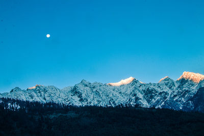 Scenic view of snowcapped mountains against blue sky