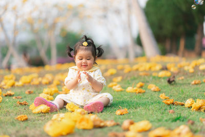 Cute girl sitting amidst flowers on field