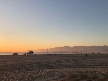 Scenic view of beach against clear sky at sunset