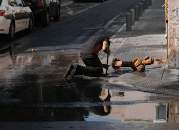 Man repairing fire hydrant on sidewalk in city