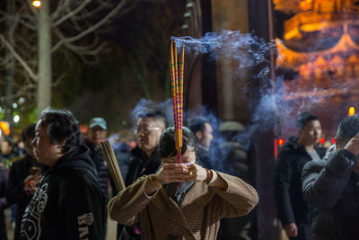 Group of people holding burning candles in temple