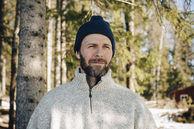 Mature man wearing knit hat looking away in forest