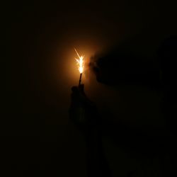 Person holding lit candle in the dark