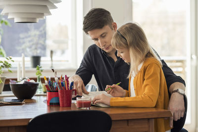 Father assisting daughter in homework at home