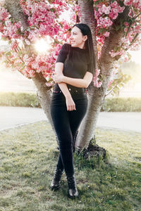 Full length portrait of young woman standing on tree