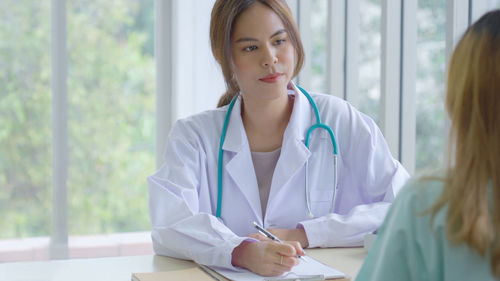 Smiling female doctor examining patient in clinic