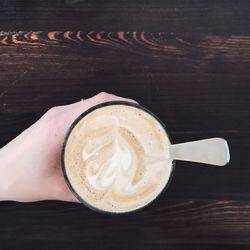 Cropped image of hand holding coffee cup on table