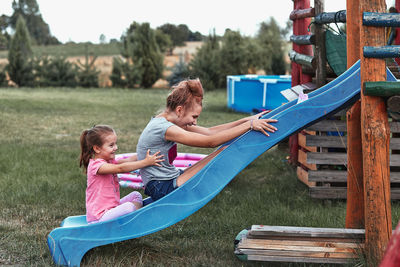 Sisters playing on slide in playground