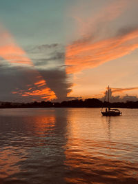 Silhouette sailboats in sea against dramatic sky during sunset