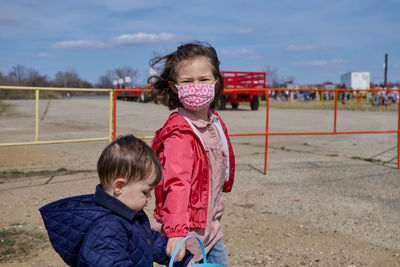 Sister leading her brother by the arm at an easter county fair