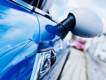 Close-up of blue car against sky