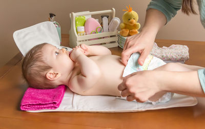 Woman changing diaper of baby girl at home
