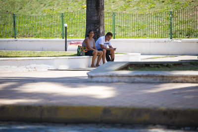 Rear view of people sitting by water