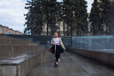Happy little cute girl having fun in splashes a fountain