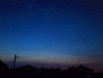 Low angle view of silhouette electricity pylon against clear sky