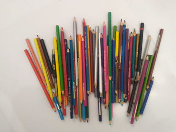 High angle view of colored pencils against white background