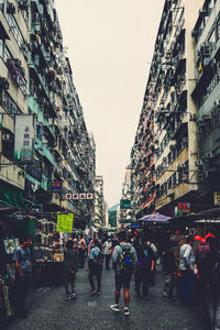 People walking on city street against clear sky