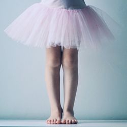 Low section of girl wearing dress while standing against wall