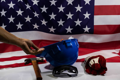 Cropped hand holding hardhat against american flag