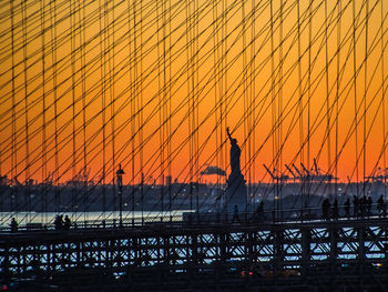 Silhouette suspension bridge against sky during sunset