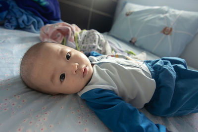 Portrait of cute baby lying on bed at home