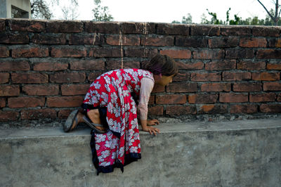 Girl kneeling on retaining wall