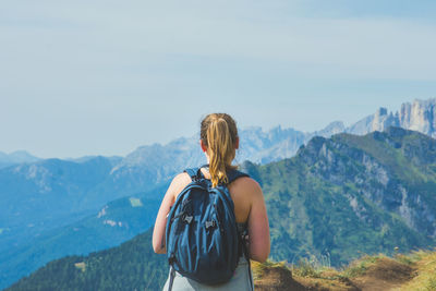 Rear view of backpacker standing on mountain against sky