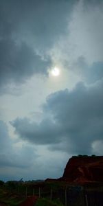 Low angle view of sun shining through clouds