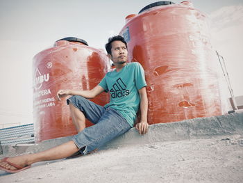 Full length of young man sitting outdoors