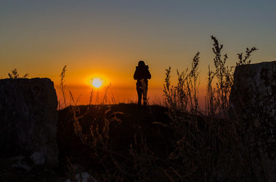 Silhouette person standing on mountain against sky during sunset