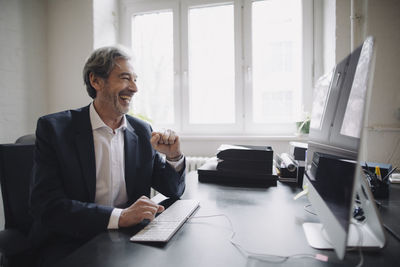 Laughing senior businessman working at desk in office