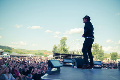 Side view of people at music concert against sky