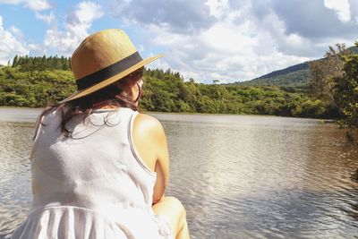 Rear view of woman looking at lake against sky