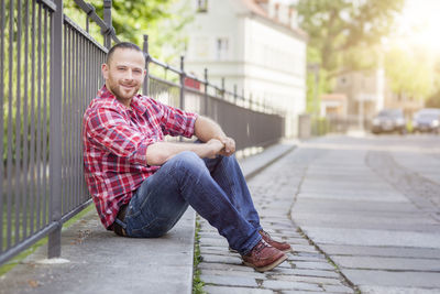 Portrait of smiling man sitting by railing