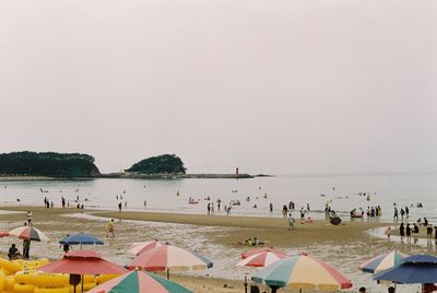 People on beach against clear sky
