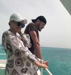 Mother and son standing on boat in sea against clear sky