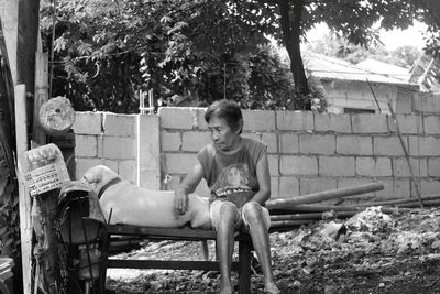 Senior woman sitting by dog in back yard