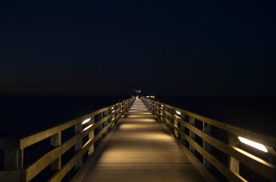 Long bridge over sea against clear sky at night