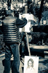 Rear view of man photographing on street in city